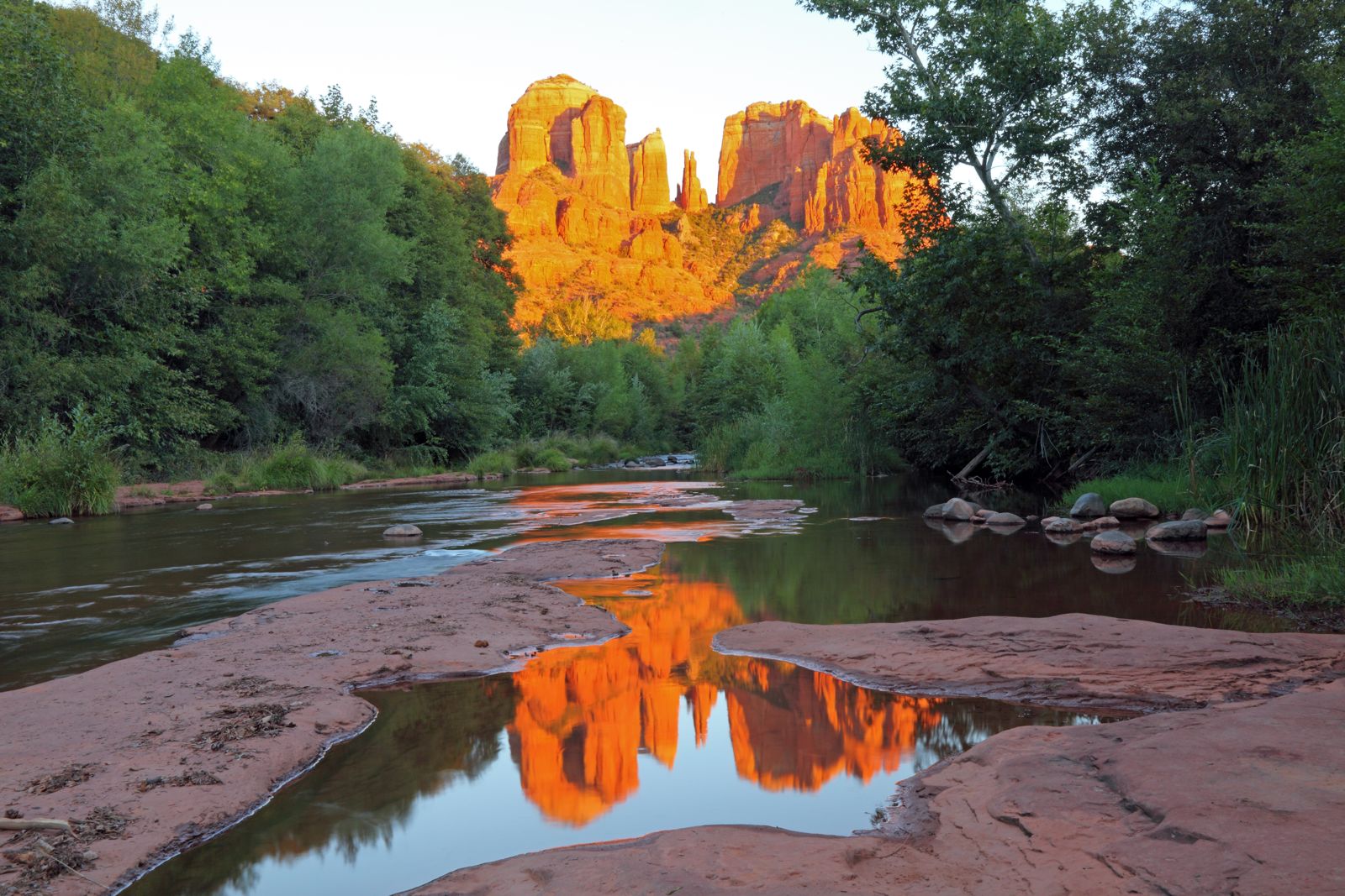 Cathedral Rock glowing orange and reflected in a pool of Oak Creek